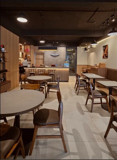 Interior hangat Plain Sight Coffee dengan kursi kayu dan pencahayaan lembut
